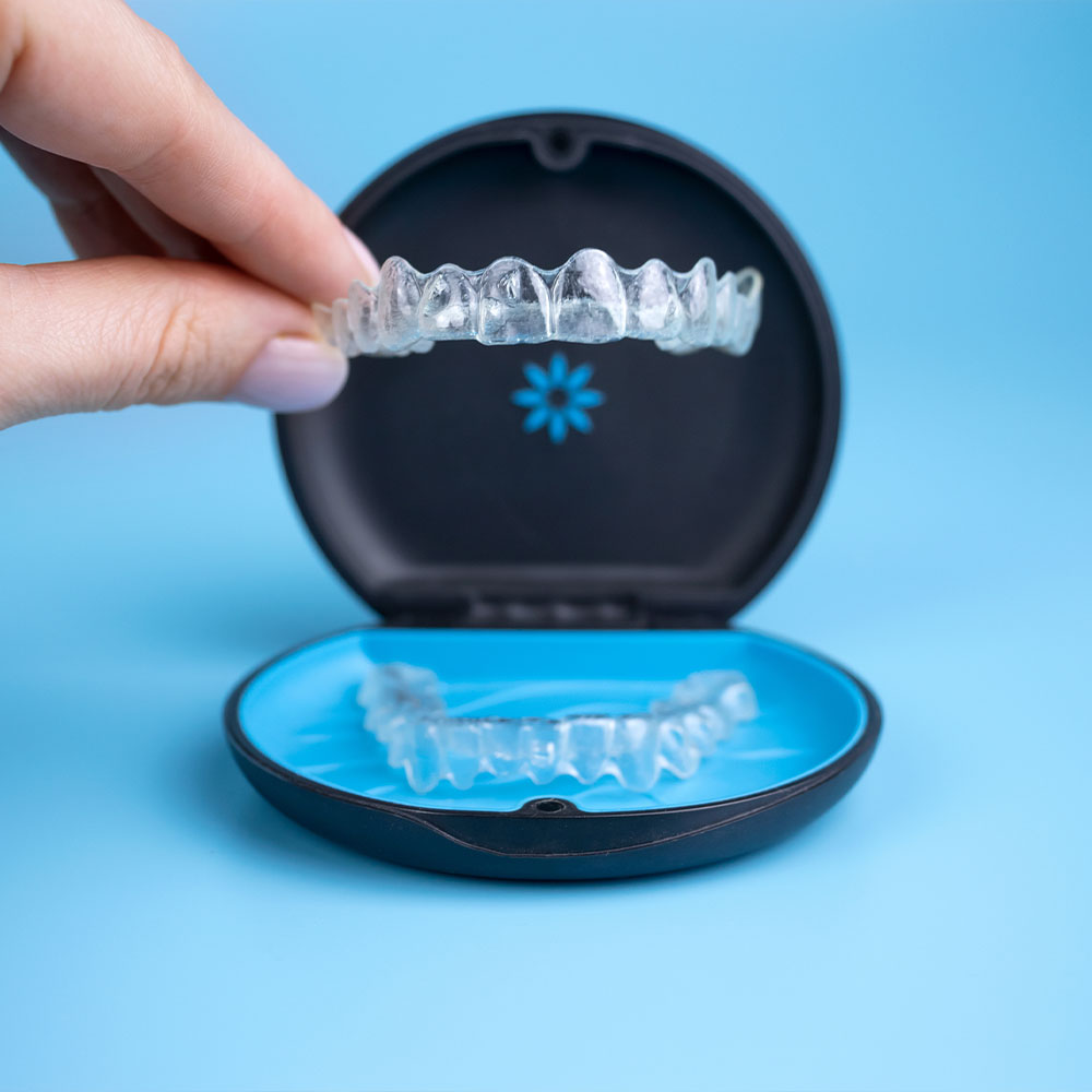A person is holding up a small, clear plastic tray with a single toothbrush-shaped object inside it.